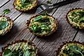 From above of cauliflower and walnut cakes with greens near fork on planked wooden table
