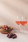 Gläser mit rotem Getränk auf einem Tisch mit einer Schale mit Trauben und Feigen