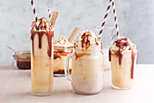 Assorted glasses with sweet caramel milkshake with vanilla ice cream and wafer cookies served on table