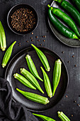 Draufsicht auf reifes grünes Superfood auf schwarzem Keramikteller neben Pfeffer in Schale auf Tisch