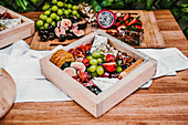 Top view of delicious fresh appetizers on wooden table near green lush shrub