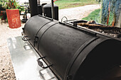 Modern black barbecue grill with closed lids placed on metal surface in outdoor cafeteria near green plants on summer day