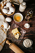 Top view of various ingredients for baking near cooking tools placed on wooden table in kitchen
