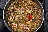 Top view of appetizing cut mushrooms cooking in metal pan with various spices on cooker during soup preparation in kitchen