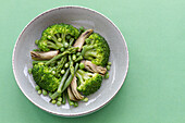 Nahaufnahme eines Gemüsegerichts mit Brokkoli, Pilzen und Erbsen von oben gesehen