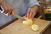 Von oben der Ernte unerkennbar weiblich in Freizeitkleidung Schneiden von Käse auf hölzernen Schneidebrett bei der Vorbereitung leckeres Abendessen in der Küche