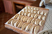 From above of raw traditional jiaozi dumplings served on wooden cutting board in kitchen
