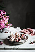Ungeschälte Knoblauchzehen auf einem Keramikteller mit Serviette auf einem Tisch in einer hellen Küche