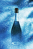 Feine Muskateller-Champagnerflasche, umgeben von glänzenden, funkelnden Lichtern und auf blauem Hintergrund