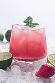 Glass of cold coconut water with strawberries served on ice background