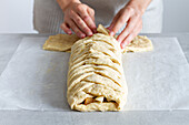 Crop unrecognizable female chef preparing delicious apple pastry with soft braided dough and fruit slices in house