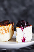 Delicious slices of baked cheesecake topped with berry jam served on a plate on black background