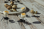 Von oben von Spielzeug schwarze Ameisen in der Nähe von Teller mit Wachteleiern auf Holztisch im Sonnenlicht platziert