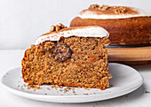 Tasty carrot cake piece with walnut and cinnamon powder on icing sugar glaze on light background