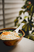 leckere asiatische Suppe mit Nudeln und Spiegelei auf einer Terrasse
