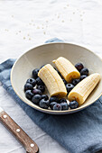 From above of round shaped bowl with ripe blueberries and cut bananas for breakfast