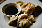 From above composition of steamed and roasted dumplings on white ceramic plate with soy sauce and chopsticks