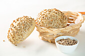 Freshly baked buns with sunflower seeds served in wicker bowl on white background