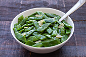 From above of healthy salad with green beans and garlic slices in bowl served on wooden table