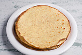 Von oben Haufen gesunder köstlicher runder Keto-Crepes mit Erythrit-Süßstoff auf Teller auf Tisch in heller Küche serviert