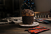 Sweet homemade baked panettone on round wooden stand near knife for celebrating Christmas