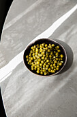 Blick von oben auf eine Schale mit leckeren Erbsen aus der Dose auf einem grauen Tisch in der Küche