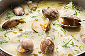 From above metal saucepan with delicious seafood soup with clams and hake
