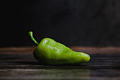 Fresh green pepper on smooth lumber table in rustic kitchen
