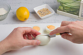 POV-Aufnahme eines nicht erkennbaren Kochs, der beim Kochen in der Küche gekochte Eier auf einem Schneidebrett schneidet