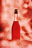 Flasche mit edler Weinrose, umgeben von glänzenden, funkelnden Lichtern, auf rotem Hintergrund