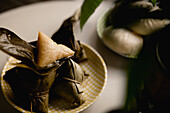Opened and covered bamboo leaf rice dumplings placed on cute checked plate