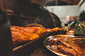 Leckeres gegrilltes Lammfleisch mit knuspriger Kruste auf einem Metallgestell in einem hellen Café während des Garvorgangs