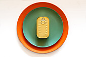 From above of rectangular closed tin can placed on green and orange round plates on white table