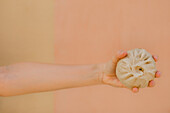 Hands of middle aged holding steamed baozi against plain background
