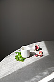 Von oben Knoblauchzehen und frische grüne Petersilie auf rundem Tisch in der Nähe von keramischen Sauciere auf grauem Hintergrund platziert