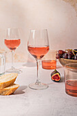 Gläser mit rotem Getränk stehen auf einem Tisch mit einer Schale mit Trauben und Feigen neben Baguettescheiben