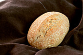 Blick von oben auf einen Laib leckeres frisches Brot auf braunem Stoff in einer Bäckerei