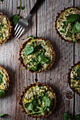 Top view of cauliflower and walnut cakes with greens near fork on planked wooden table