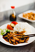 Appetitlich gekochte Yuxiang-Aubergine mit gesundem Gemüse und Reis auf weißem Teller in asiatischem Restaurant