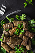 From above of palatable sarma with parsley and fork on dark background