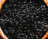 Closeup top view of wooden bowl with heap of natural black rice for lunch
