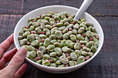 Top view of frozen broad beans in bowl served on rustic wooden table