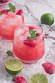 From above of glasses of cold coconut water with strawberries served on ice background