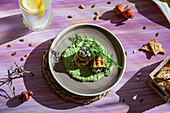Großaufnahme von leckeren gebratenen Zucchiniröllchen mit Füllung auf Püree mit Dill auf einem Tisch mit kaltem Erfrischungsgetränk