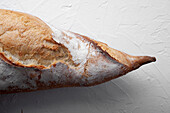 Appetizing freshly baked baguette with crispy crust placed on white table