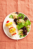 Frischer veganer Teller mit Gemüsespieß und mariniertem Tofu, serviert mit einem gemischten Salat