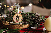 Weihnachtlich gedeckter Tisch mit Kranz und dekorativen Holzornamenten und rot karierter Tischdecke mit gelben Lichtern im Hintergrund