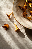 High angle of chanterelle mushroom placed on table near bowl at sunlight in countryside home