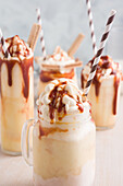 Assorted glasses with sweet caramel milkshake with vanilla ice cream and wafer cookies served on table