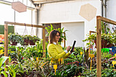 Female gardener using modern tablet while counting plants and working in garden center